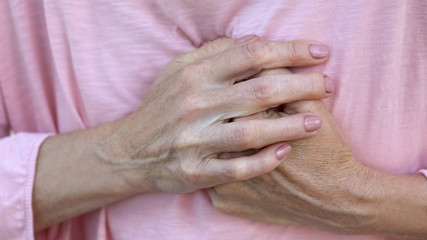 Old lady holds hands on chest, progressive breast cancer, bad diagnosis, pain