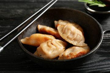 Frying pan with tasty Japanese gyoza on dark wooden table