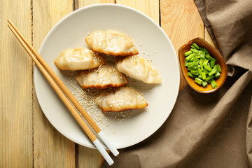 Plate with tasty Japanese gyoza on wooden table