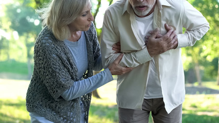 Aged man having heart pain during walk with wife, heart attack, healthcare
