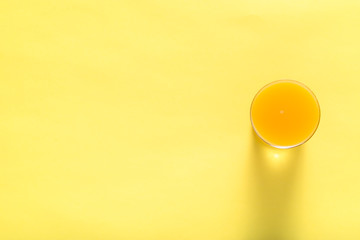 Glass of fresh juice, top view. Orange juice on yellow background.