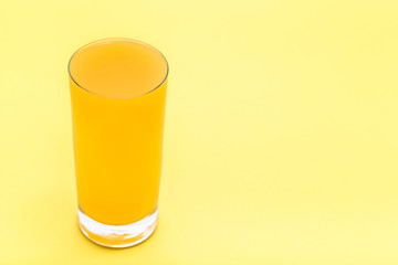 Fresh juice in a glass. Orange juice on yellow background