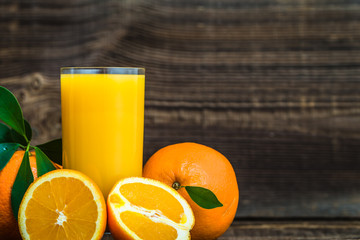 Freshly squeezed orange juice and fresh oranges on wooden table