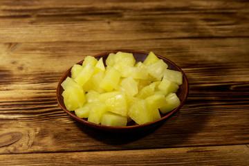 Canned pineapple pieces in ceramic plate on wooden table