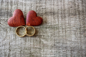 Wedding rings and red heart on wooden background