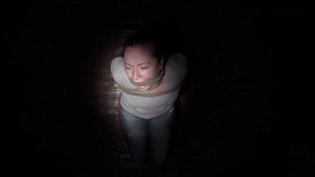 bound prisoner to chair sits in dark room under beam of light. top view.