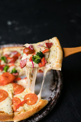 Tasty sliced pizza with basil leaves on black table