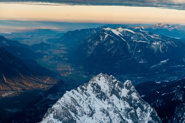 Scenic aerial view of snowy Zugspitze mountains, hills and valley on sunset in Bavarian Alps, Germany.
