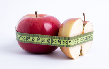 fresh red apple and sliced half with green measuring tape closeup on white background. healthy vegetarian organic food for diet planning, fitness and lose weight