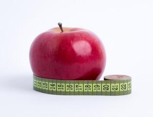 fresh red apple with green measuring tape closeup on white background. healthy vegetarian organic food for diet planning, fitness and lose weight