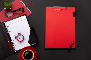 Black background red coffee cup notepad alarm clock flower diary scores keyboard on the table. Top...