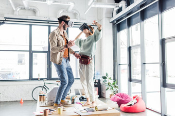 female and male designers wearing vr headset, gesturing with hands and having virtual reality experience in loft office