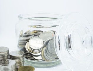 Coins in glass jar isolated on white background. Saving money concept.