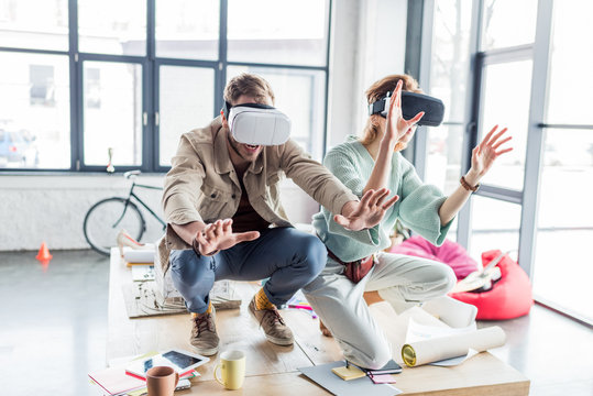 excited female and male architects gesturing with hands while having virtual reality experience in loft office