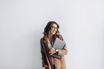 Happy business woman in a glasses with a laptop in her hands in the office with copy space