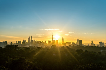 Cityscape of Kuala Lumpur, Malaysia surrounded by trees during sunrise
