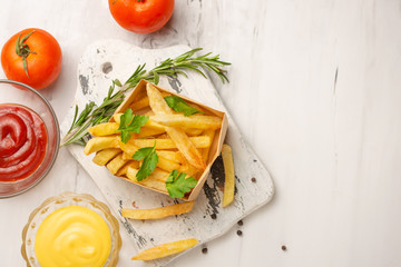 French fries with rosemary and cheese and tomato sauce on a light background. Delicious and harmful food