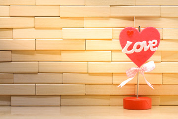 Happy valentine's day concept. Love word and red heart shape on wall made from wooden blocks under sunlight with copy space for wallpaper or background
