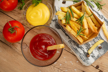 Flat-lay tasty and fresh french fries with different sauces and vegetables. Top view background