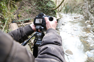 photographer with digital camera and tripod outdoors
