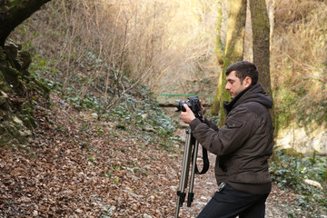 videographer shoots video from a tripod in a forest in the mountains