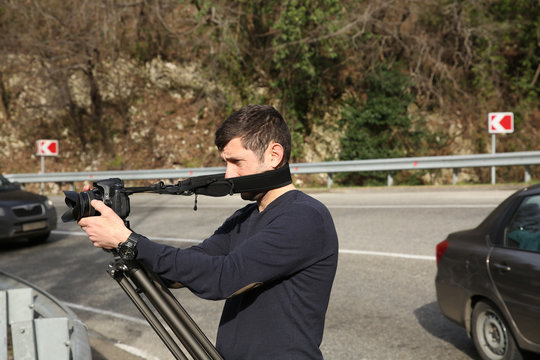 videographer shoots video with a tripod on the road