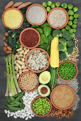 Healthy high protein super food with fresh vegetables,legumes, grains, seeds and nuts, health foods high in dietary fibre, vitamins and antioxidants. Top view on rustic wood background.