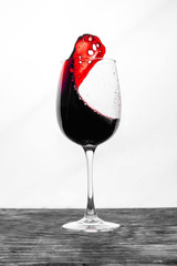 Red wine in the glass splashes in motion on a white background. Design card