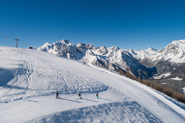 Fototapeta na wymiar Skiers and snowboarders on the track, ski station in the Italian Alps. Valtellina.