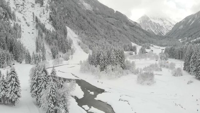 Beautiful aerial view of the mountain river in winter in the valley of snow-capp