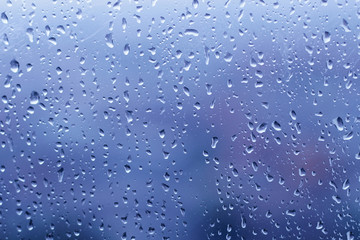 raindrops on glass window in blue background