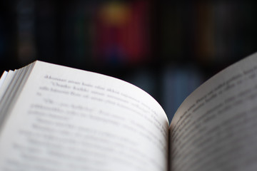 Open book with blurry bookcase in the background. Selective focus. Concept for reading.