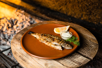 fried fish with lemon and gravy on a clay plate