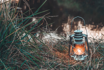 Fototapeta premium Kerosene lamp on the background of the lake and nature.