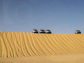 Fototapeta na wymiar Cars on top of the dune in the desert