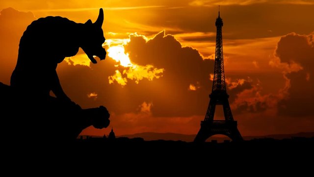 Paris: Gargoyle or chimera on the Gothic Cathedral of Notre Dame looks at the Eiffel Tower and city Skyline at Sunset, France. Gargoyles are old demon statue in French Culture