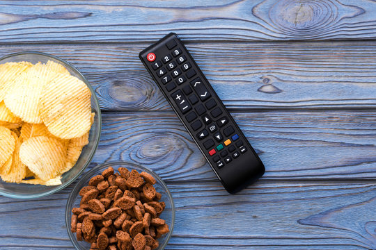 chips, crackers, remote control on a wooden background. fast food, watching TV, relaxing.