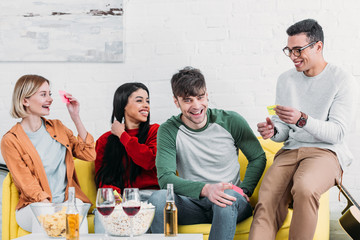 multicultural friends joking and fixing stickers on foreheads