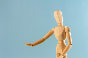 Wooden model with hands up on neutral background.