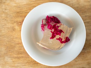 Plate with Ukrainian aspic flavored with horse-radish pickled in beetroot juice standing on wooden surface 