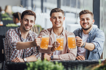 Three young man resting at cafe with a glass of beer