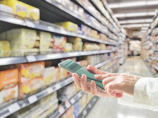 Digital lifestyle business person or shopper using mobile smart phone for retail shopping in supermarket