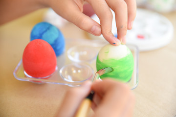 Obraz na płótnie Canvas Happy Easter Day. Easter eggs concept. A girl hand painting Easter eggs. Happy family preparing for Easter.