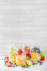 Fototapeta na wymiar Selection various fruit and berry lemonade drinks, refreshment infused water, in mason jars, with fresh strawberry, lemon, lime, oranges, blueberry, copy space