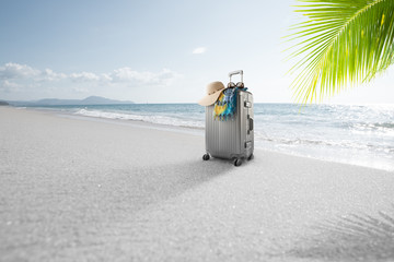 View of gray suitcase with pareo and hat on tropical  beach 