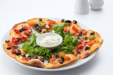 close up view of crispy chips topped with black beans, pico de gallo and cheese.on white back