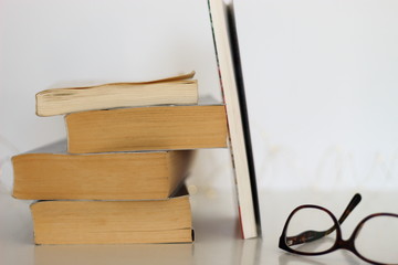 Books with vintage glasses on a white table.