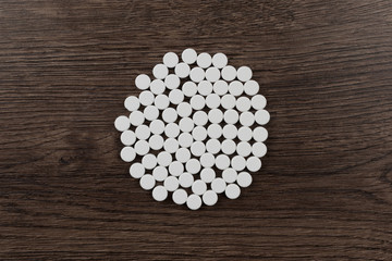 White tablets are arranged in a circle on a wooden table