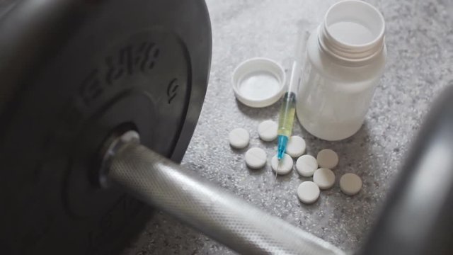 White steroid pills and syringe with dumbbell - doping in sport