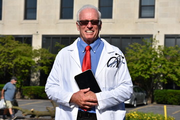 Smiling Handsome Senior Male Doctor Wearing Lab Coat With Tablet At Hospital